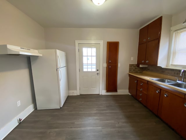 kitchen featuring a wealth of natural light, under cabinet range hood, a sink, and freestanding refrigerator