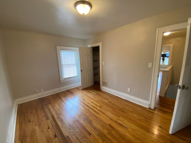 unfurnished bedroom featuring baseboards, wood finished floors, visible vents, and a closet