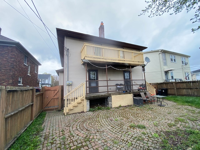 rear view of house featuring a gate, a chimney, and a fenced backyard