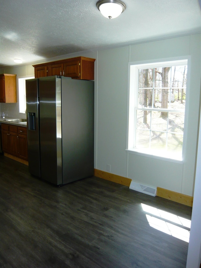kitchen featuring a textured ceiling, dark wood-style floors, visible vents, and stainless steel refrigerator with ice dispenser