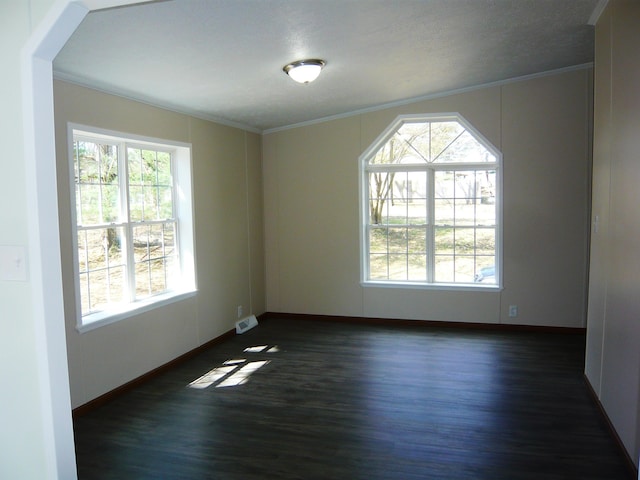 unfurnished room featuring dark wood finished floors, ornamental molding, and plenty of natural light