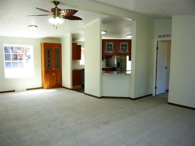 unfurnished living room with carpet, visible vents, baseboards, and ceiling fan