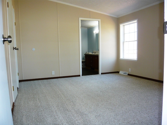 unfurnished bedroom with baseboards, ornamental molding, ensuite bathroom, carpet floors, and visible vents