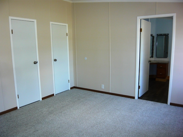 unfurnished bedroom with carpet floors, baseboards, and ensuite bath