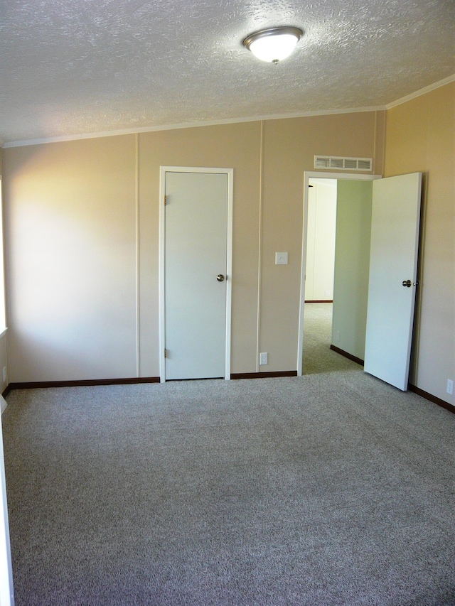 empty room with crown molding, a textured ceiling, visible vents, carpet flooring, and baseboards