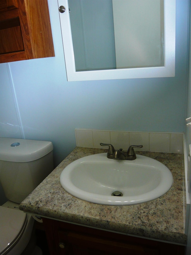half bathroom featuring vanity and toilet