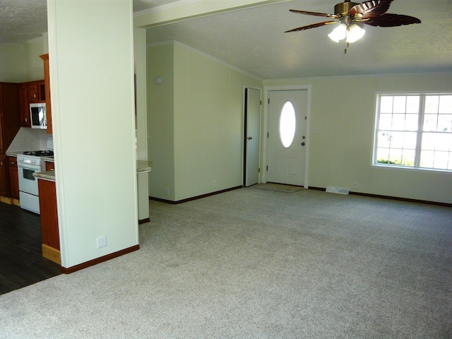 foyer featuring baseboards, ornamental molding, a ceiling fan, carpet floors, and visible vents