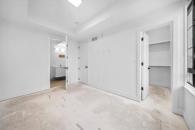 533 E Harrison Ave Unit 30, Royal Oak, MI 48067 - unfurnished bedroom with a raised ceiling, ensuite bathroom, a walk in closet, and visible vents