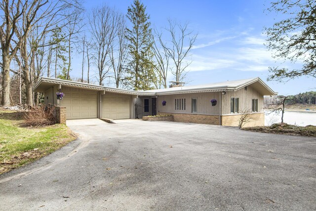 3942 Harmon Dr, Fremont, MI 49412 - ranch-style home with a garage, aphalt driveway, and brick siding