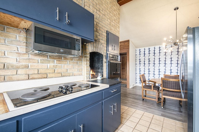 3942 Harmon Dr, Fremont, MI 49412 - kitchen featuring black appliances, blue cabinetry, light tile patterned flooring, and vaulted ceiling