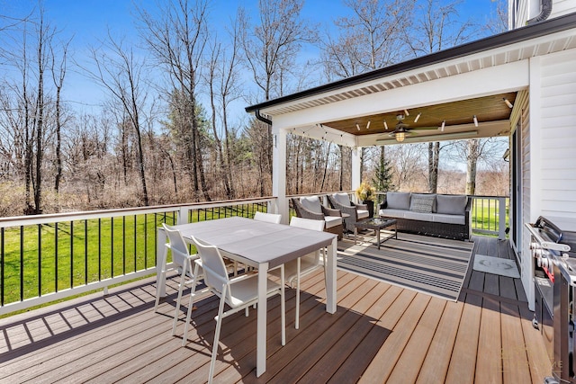 wooden terrace featuring an outdoor living space, a ceiling fan, outdoor dining area, and a lawn