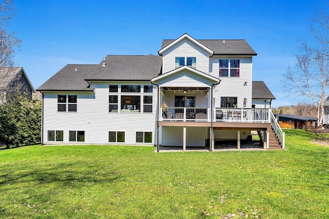 back of property featuring roof with shingles, a deck, a lawn, and stairs