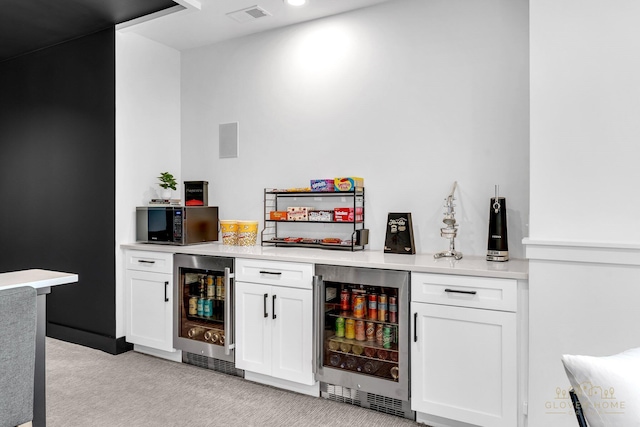 bar with visible vents, a dry bar, beverage cooler, and light carpet