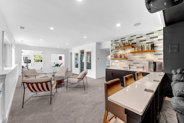bar with wet bar, visible vents, light carpet, a sink, and backsplash