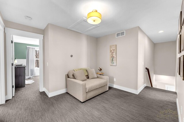 sitting room with baseboards, an upstairs landing, attic access, visible vents, and carpet