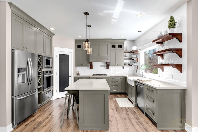 kitchen with a center island, open shelves, a warming drawer, gray cabinetry, and stainless steel appliances