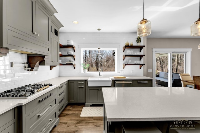 kitchen featuring open shelves, a sink, dark wood-style floors, stainless steel appliances, and gray cabinets