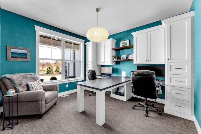 carpeted home office with built in study area, visible vents, and baseboards