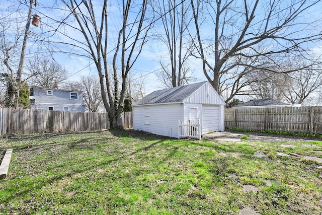 view of yard with a garage, a fenced backyard, and an outbuilding