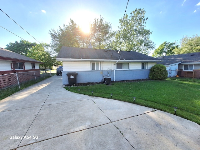 7541 Sloan St, Taylor, MI 48180 - rear view of property featuring central AC, a lawn, fence, concrete driveway, and brick siding