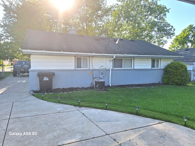 7541 Sloan St, Taylor, MI 48180 - rear view of property with brick siding, central AC unit, a lawn, and a chimney