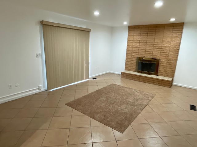 unfurnished living room featuring baseboards, tile patterned floors, recessed lighting, a brick fireplace, and visible vents