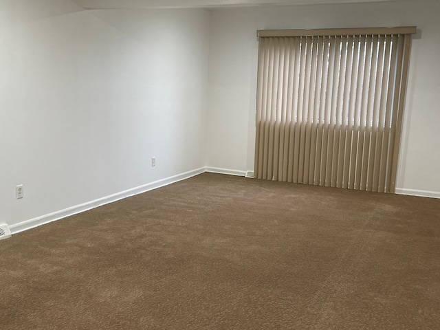 empty room featuring visible vents, baseboards, and dark carpet
