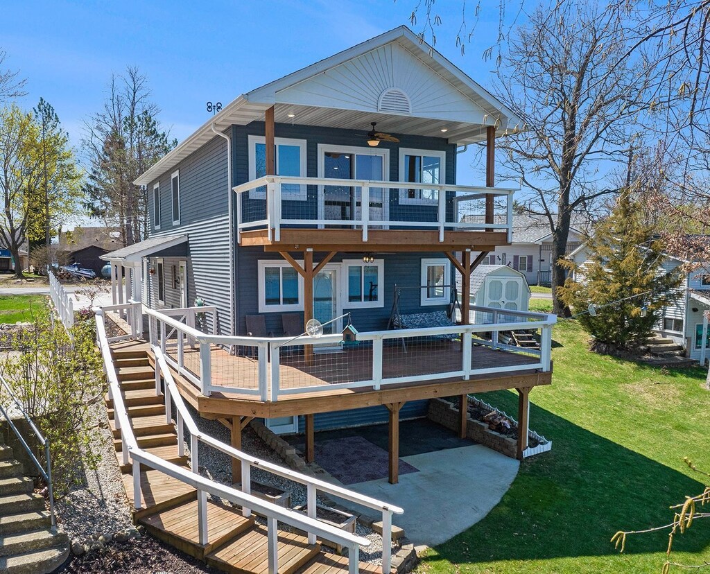 11010 Woodward Dr, Byron, MI 48418 - rear view of property featuring a ceiling fan, stairs, a yard, a storage unit, and a deck