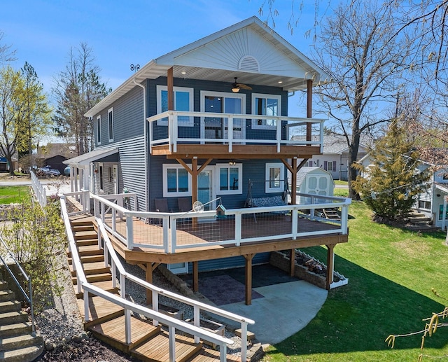 rear view of property featuring a ceiling fan, stairs, a yard, a storage unit, and a deck