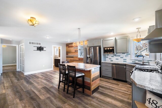 kitchen with a sink, stainless steel appliances, dark wood finished floors, gray cabinetry, and visible vents