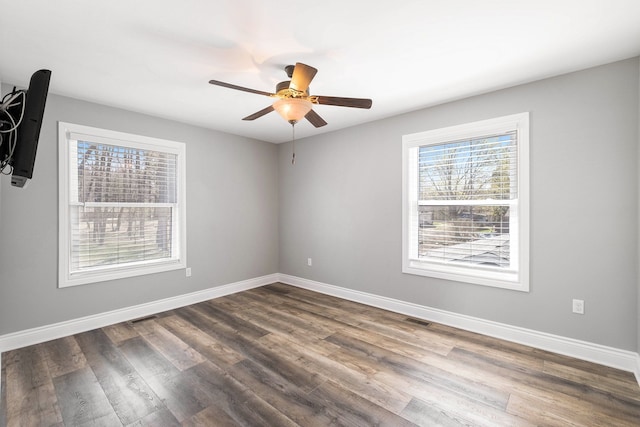 spare room with dark wood-style floors, baseboards, a ceiling fan, and visible vents