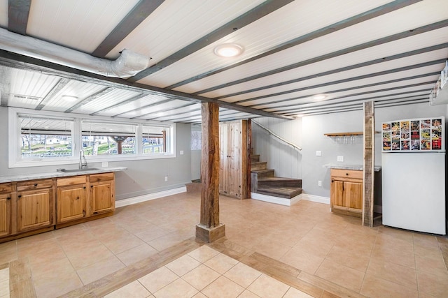 below grade area featuring light tile patterned floors, a sink, visible vents, baseboards, and stairs