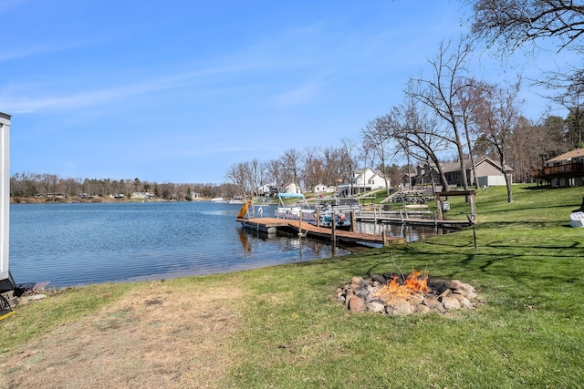view of dock with a lawn, a fire pit, and a water view
