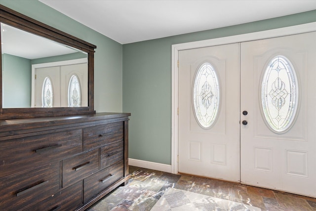 entryway featuring baseboards, stone finish floor, and a healthy amount of sunlight