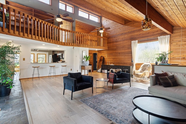 living room with wooden walls, a ceiling fan, and wood finished floors