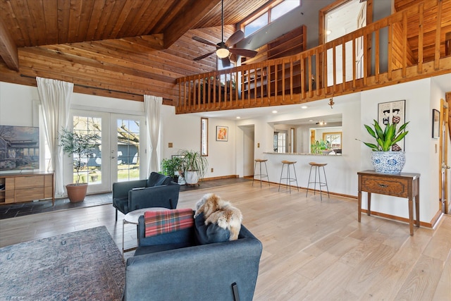 living area with wood finished floors, baseboards, high vaulted ceiling, a ceiling fan, and french doors