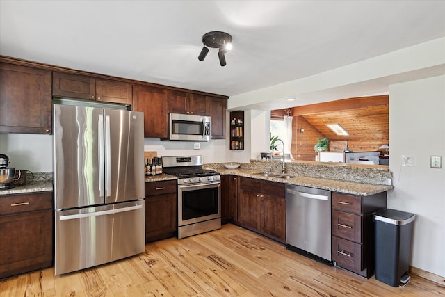 kitchen with light stone counters, light wood-style flooring, a sink, stainless steel appliances, and dark brown cabinetry