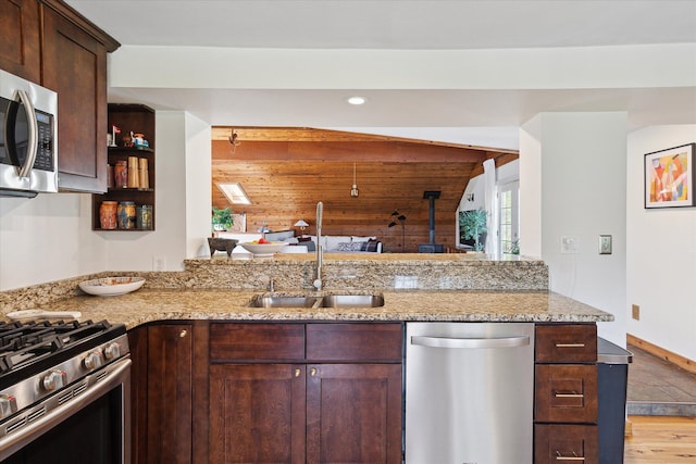 kitchen featuring light stone countertops, stainless steel appliances, dark brown cabinets, and a sink