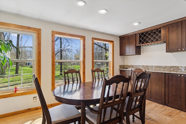 dining area featuring light wood-style floors, recessed lighting, a bar, and baseboards