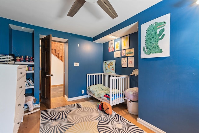bedroom featuring baseboards, wood finished floors, and a ceiling fan