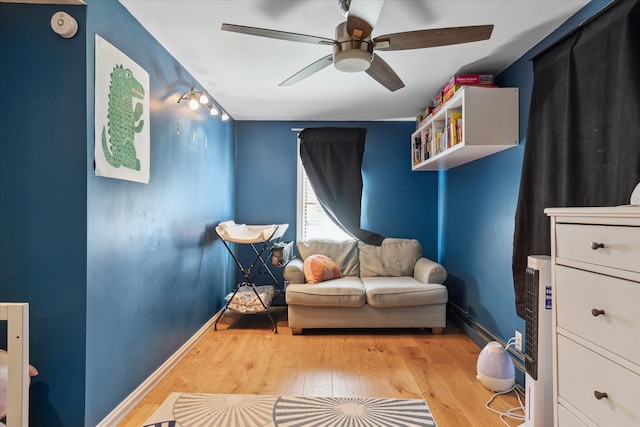 sitting room featuring wood-type flooring, ceiling fan, and baseboards