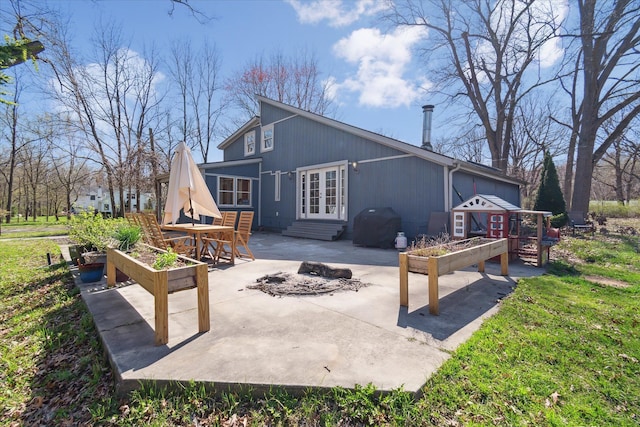 rear view of house with a vegetable garden, entry steps, french doors, and a patio area