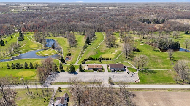 aerial view featuring a forest view, a water view, and view of golf course