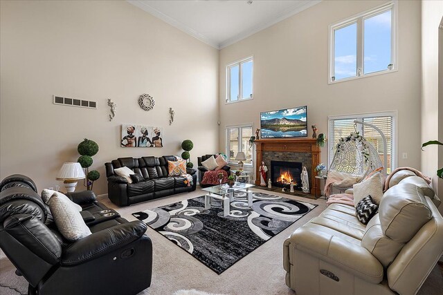 living area with a high ceiling, ornamental molding, a glass covered fireplace, and carpet floors