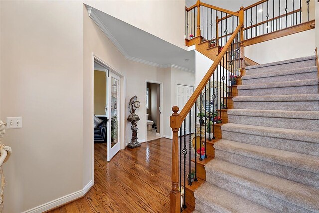 staircase featuring wood finished floors, baseboards, and ornamental molding