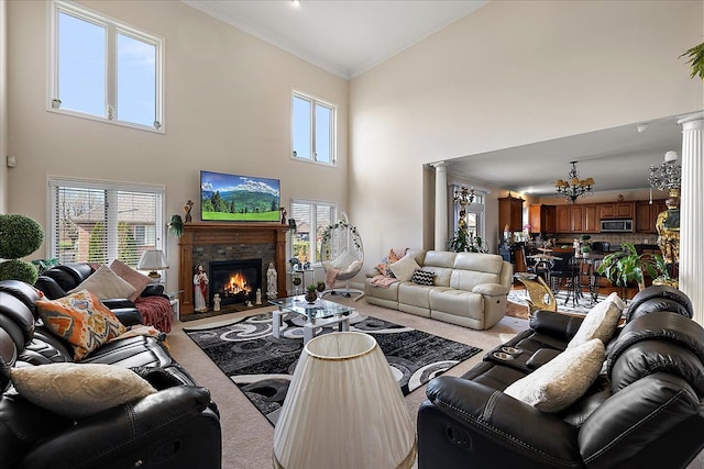 carpeted living room featuring a chandelier, crown molding, a towering ceiling, and decorative columns
