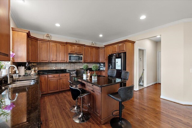 kitchen with dark wood finished floors, appliances with stainless steel finishes, a center island, and a sink