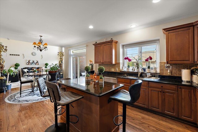 kitchen with a kitchen breakfast bar, a notable chandelier, wood finished floors, and a sink