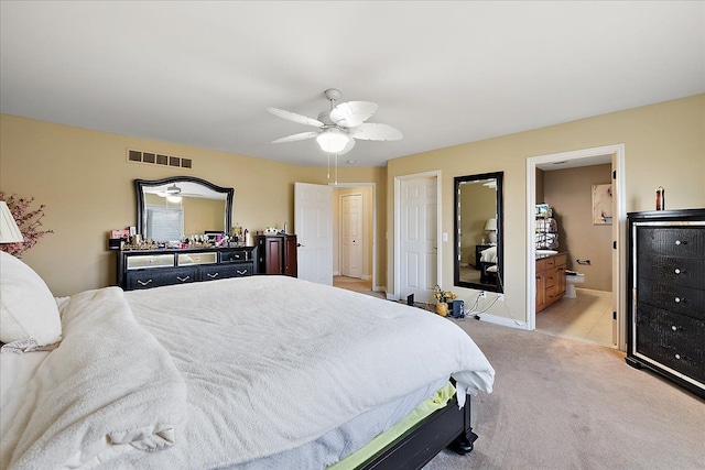 bedroom with a ceiling fan, ensuite bathroom, light carpet, baseboards, and visible vents
