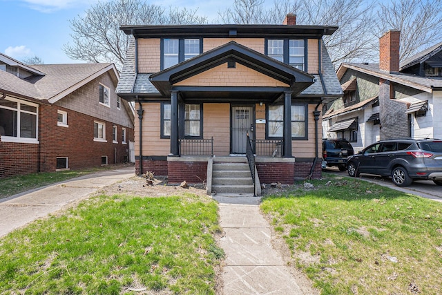 view of front facade featuring a chimney, a front lawn, and covered porch